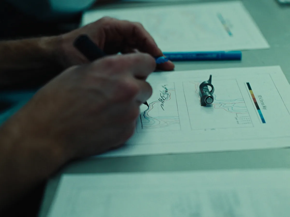 Engineer annotating a printed FEA stress-map diagram